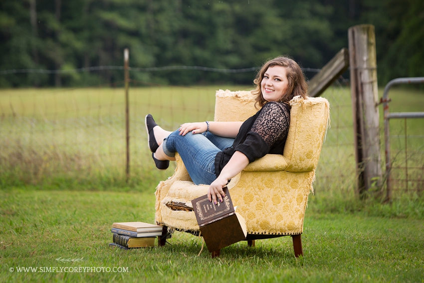 senior girl in a chair with books by Carrollton senior portrait photographer