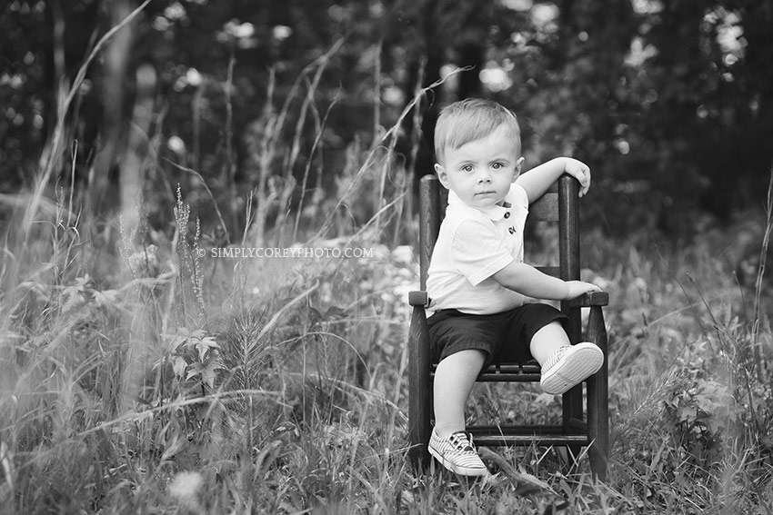Villa Rica baby photographer, toddler boy in a rocking chair outside in black and white