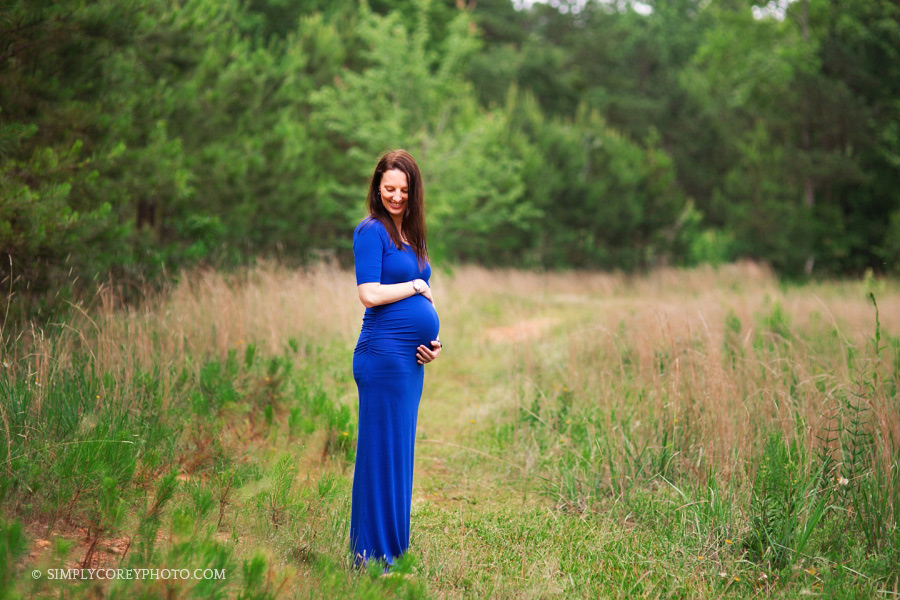 expecting mom in blue dress outside by Douglasville maternity photographer