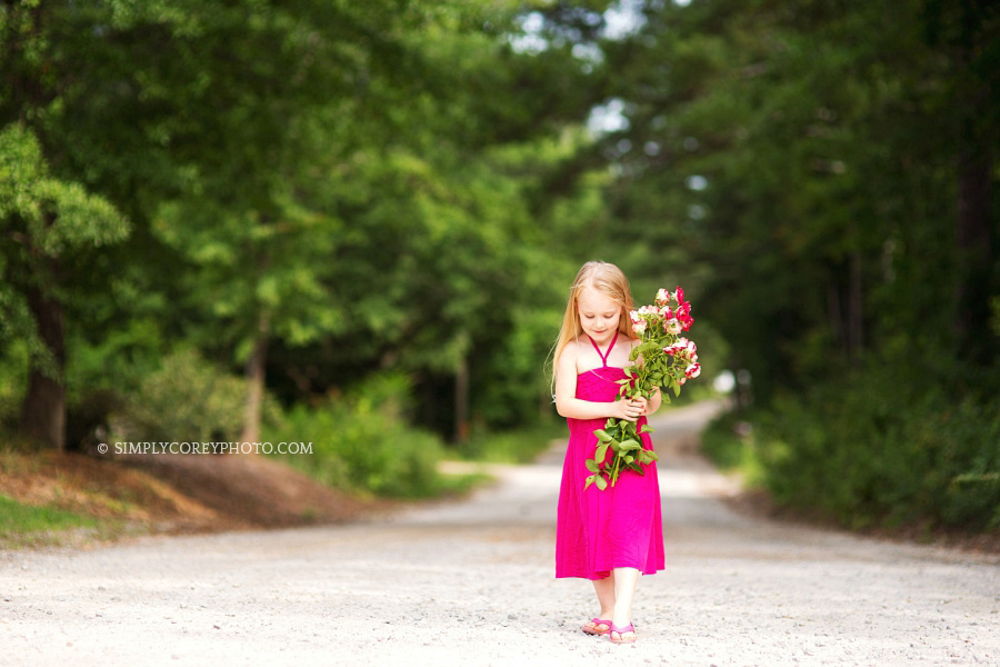 girl holding pink flowers on a country road by Atlanta children's photographer