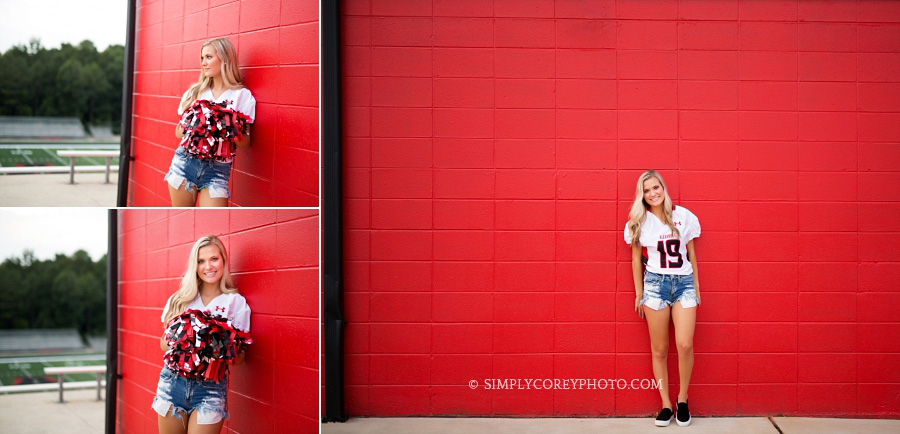 Alexander High School cheerleader near a red wall by Douglasville senior portrait photographer