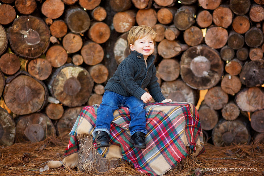 toddler boy near a wood pile by Atlanta baby photographer