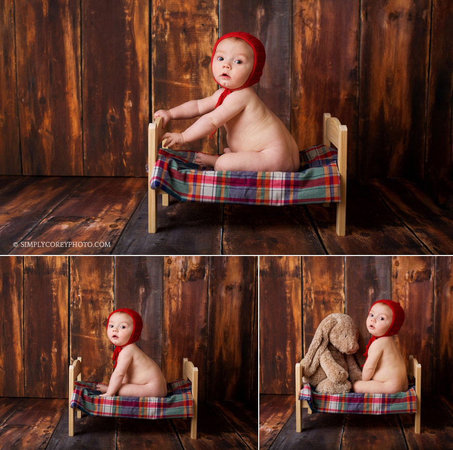 baby photographer Newnan; boy in a red hat sitting on a bed in studio