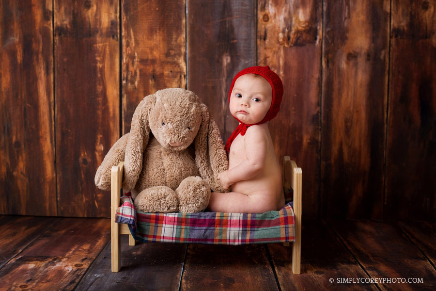 Newnan baby photographer, boy in a red hat sitting on a bed with a bunny in studio