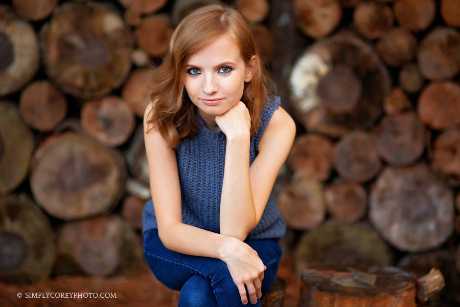 Newnan senior photographer, teen girl sitting in front of a log wall