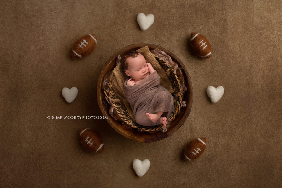 Atlanta newborn photography of a baby boy in a basket with footballs