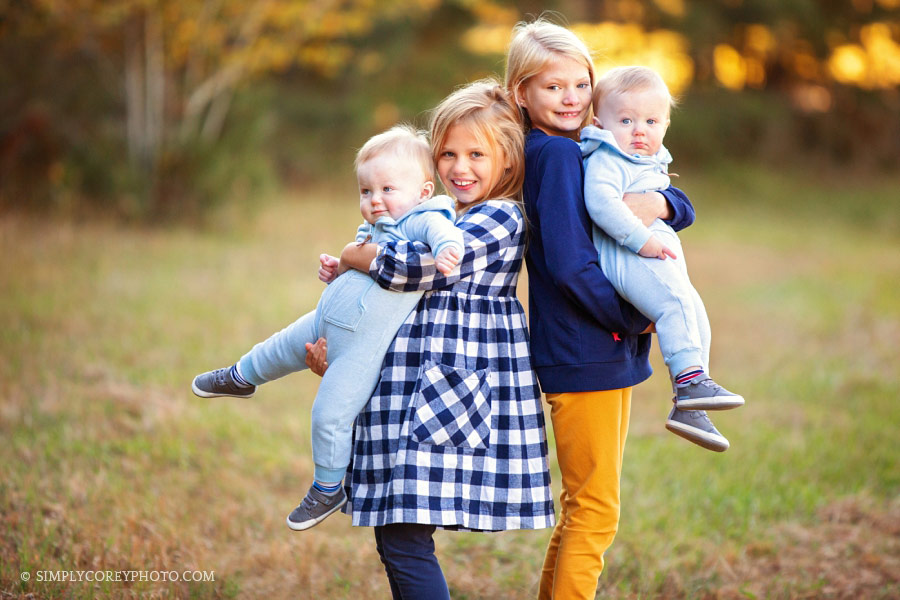 Newnan family photographer, sisters holding twin baby brothers