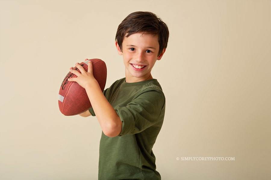 Carrollton children's photographer, tween boy with a football in studio