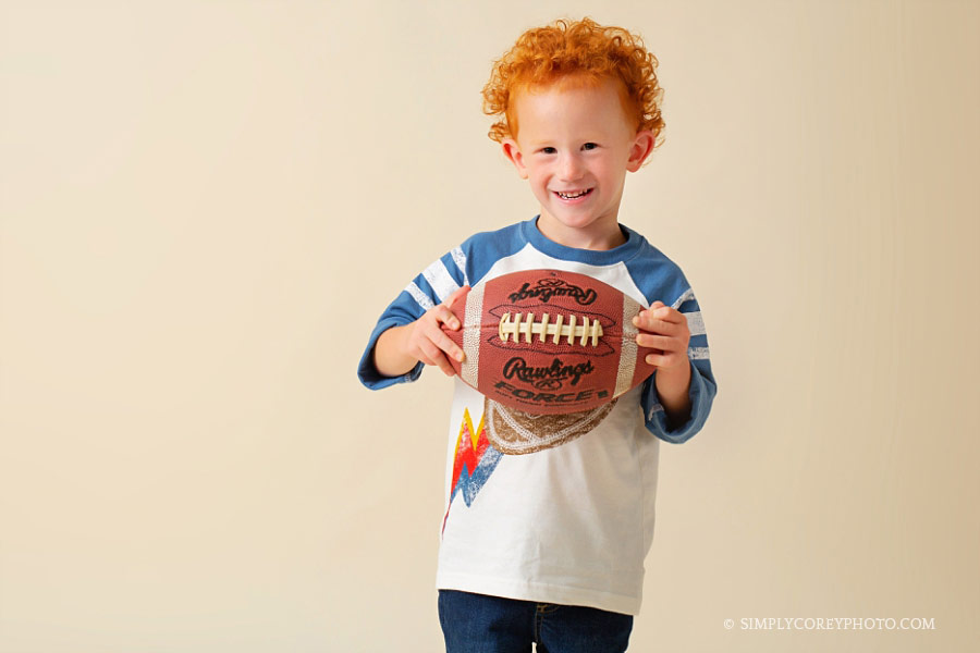 Douglasville children's photographer, studio photo of a redhead boy with a football