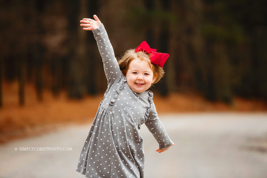 Atlanta children's photographer, child in red bow outside with arms wide open