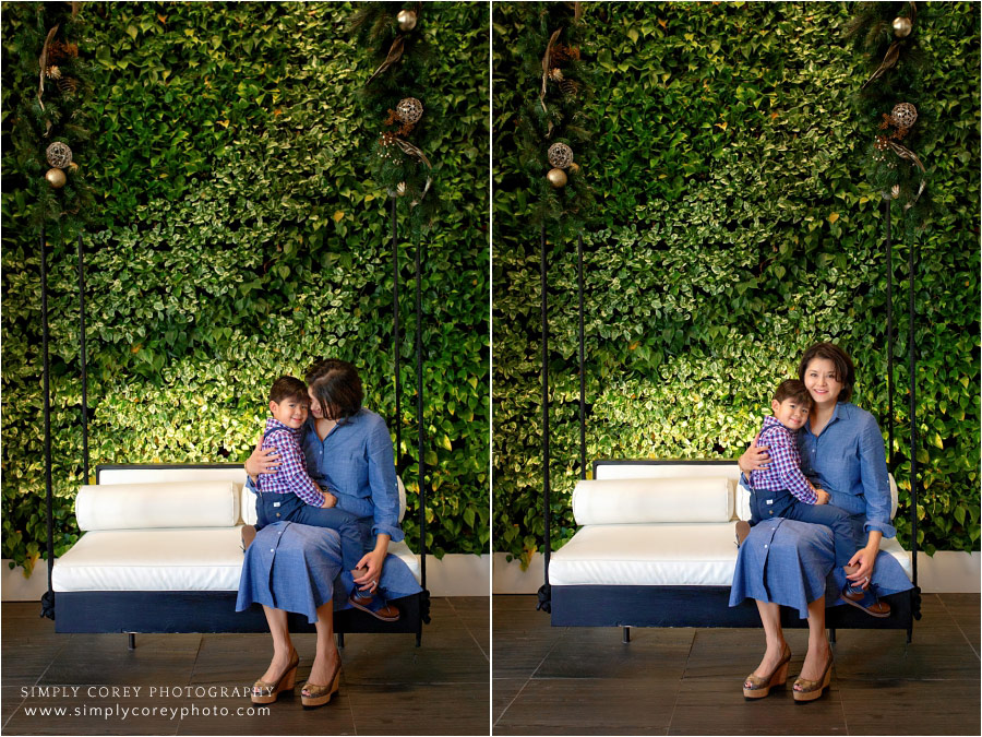 Carrollton family photographer, mom and child sitting by greenery wall in Atlanta hotel