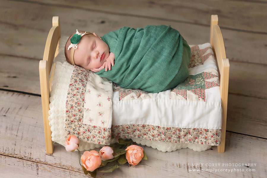 newborn photographer near Carrollton, Georgia; baby in teal on bed with quilt