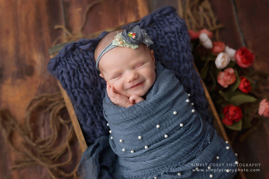 newborn photographer near Villa Rica, smiling baby girl in blue with flowers