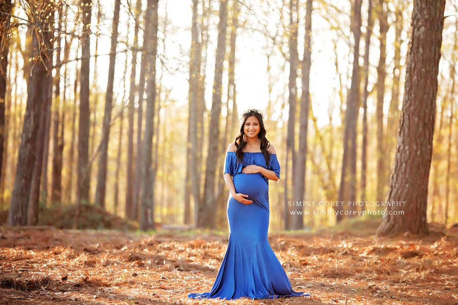 Atlanta maternity photographer, mom outside in blue dress by pine trees