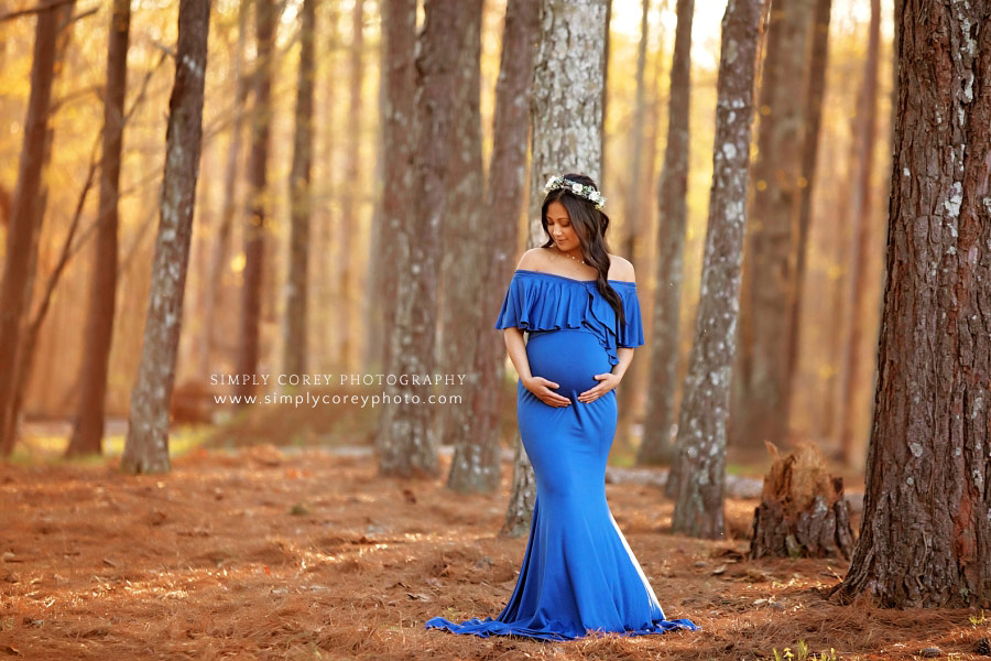 Newnan maternity photographer, mom in blue dress outside by trees
