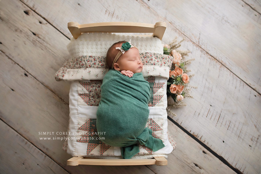 Douglasville newborn photographer; baby girl in teal on quilted bed with flowers