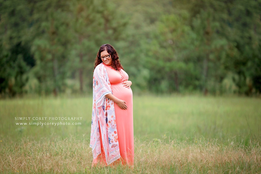 maternity photographer near Carrollton, GA; expecting mom outside in a coral dress and kimono