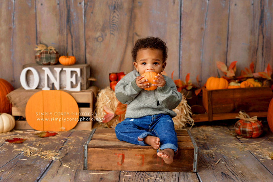 Peachtree City baby photographer, one year old boy holding small pumpkin