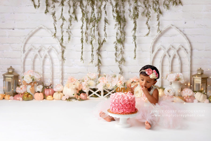 cake smash photographer near Carrollton, GA; baby girl in studio with pink pumpkins