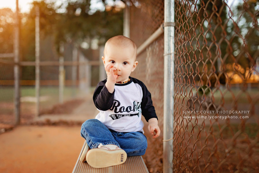 Atlanta baby photographer, one year old on bench in baseball dugout