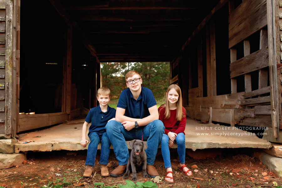 Carrollton family photographer in Georgia; kids in old barn with puppy