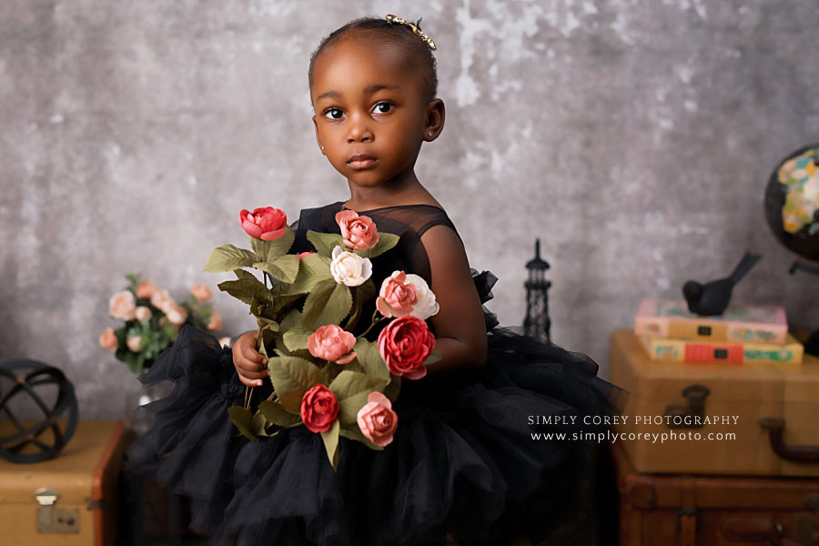 baby photographer near Atlanta, two year portrait in black dress and holding flowers 