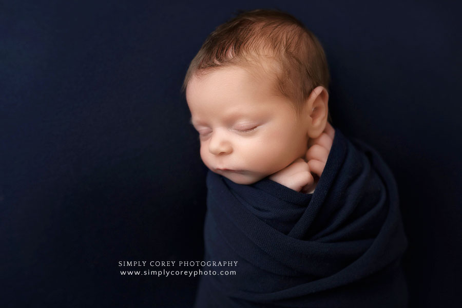 Dallas, GA newborn photographer; baby boy with blue swaddle and studio backdrop