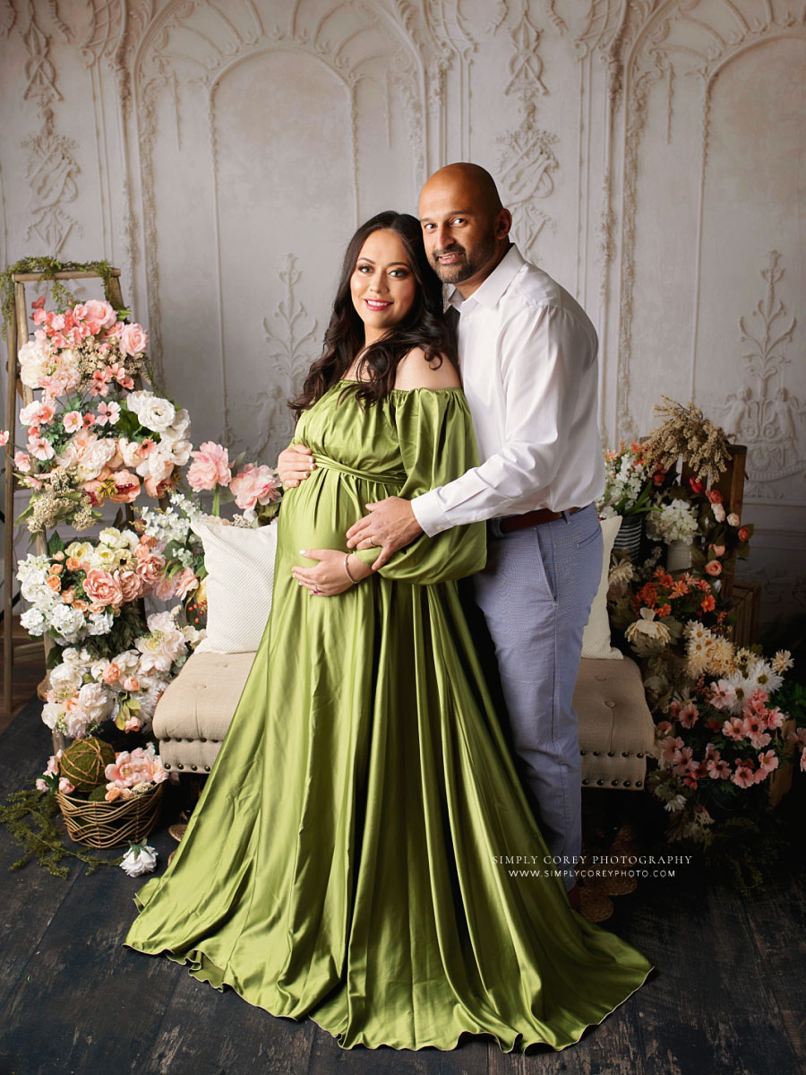 maternity photographer near Villa Rica, expecting couple in studio with green dress and flowers