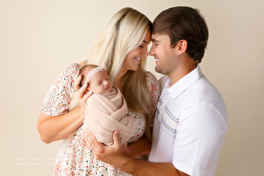newborn photographer near Carrollton, GA; parents holding baby girl during studio session
