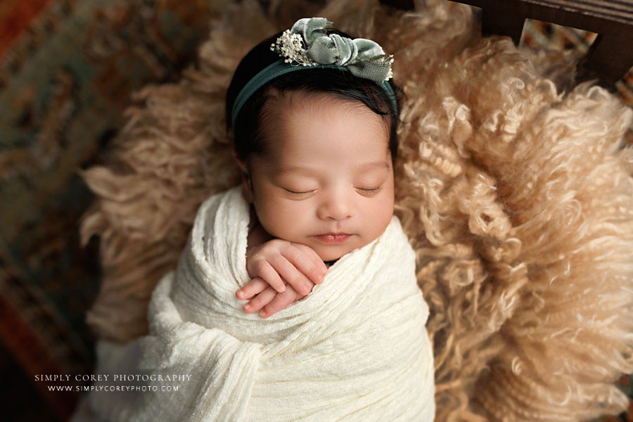 newborn photographer near Carrollton, GA; baby girl in ivory wrap on flokati