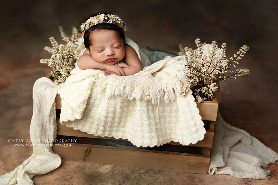 newborn photographer near Dallas, GA; baby girl in crate with ivory layers and flowers