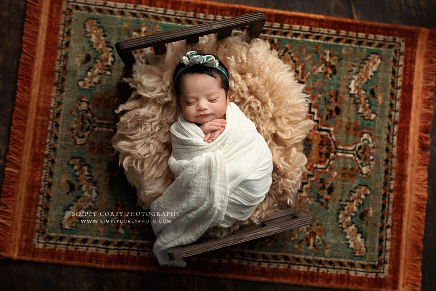 newborn photographer near Powder Springs, baby girl on flokati with orange and green rug