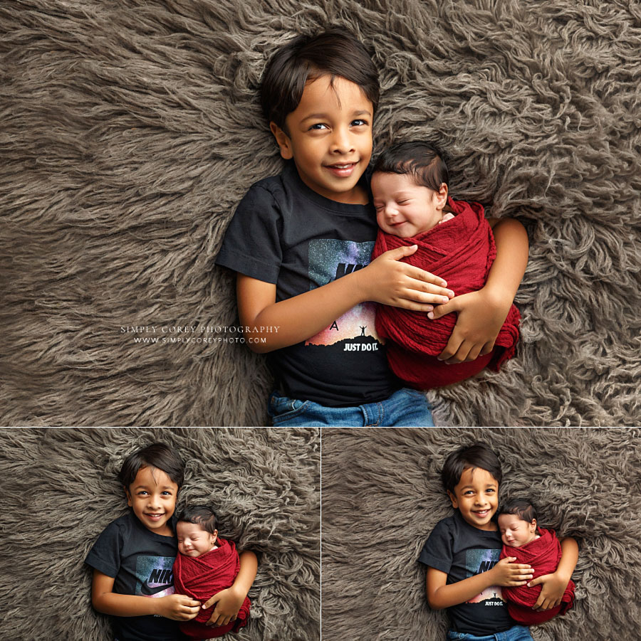Villa Rica family photographer, big brother holding smiling newborn baby sister on flokati