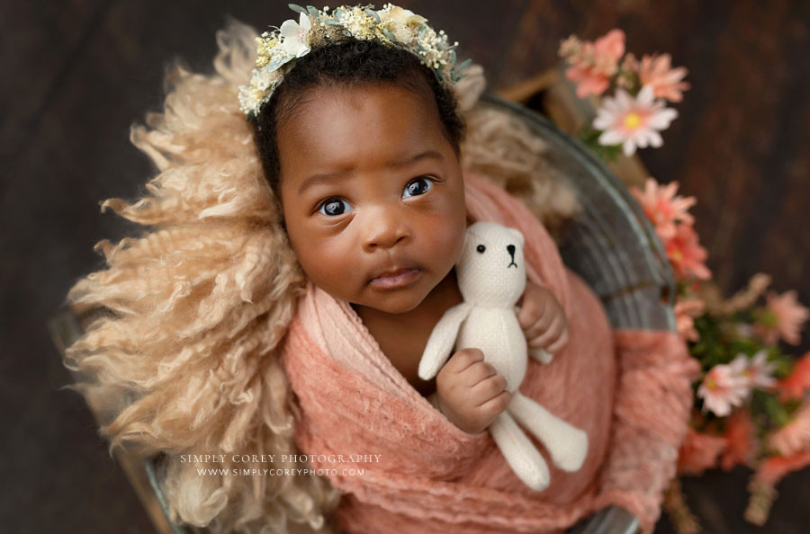 newborn photographer near Newnan, awake baby girl in bucket with flowers and teddy bear 