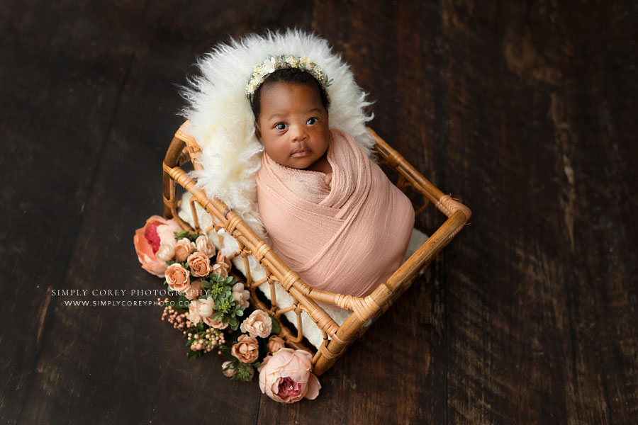 newnan newborn photographer, awake baby girl in pink swaddle and rattan bed with flowers