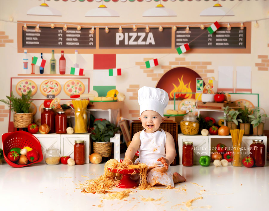 Carrollton baby photographer in Georgia, boy in chef hat and apron with spaghetti in studio