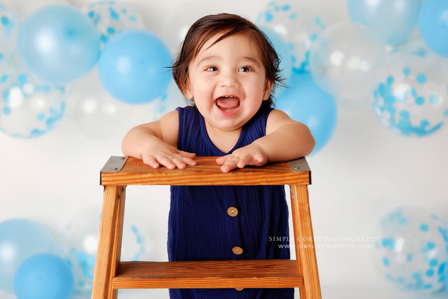 Carrollton baby photographer in Georgia, boy smiling with blue and white balloons in studio