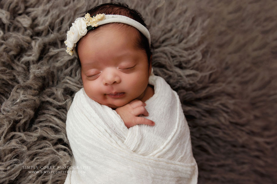 Carrollton newborn photographer in GA; baby girl smiling in ivory wrap
