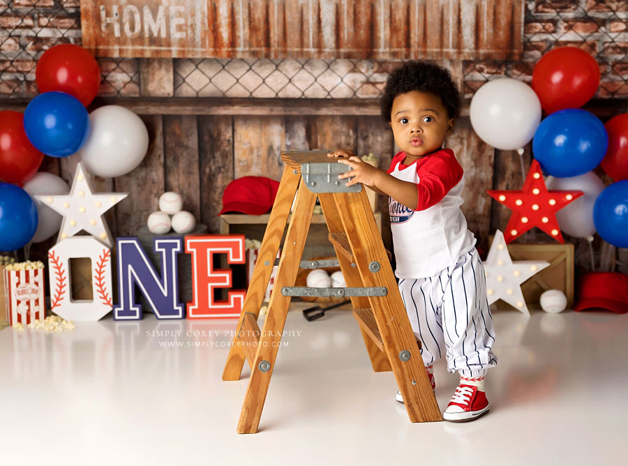 baby photographer near Douglasville, one year old with ladder on baseball set