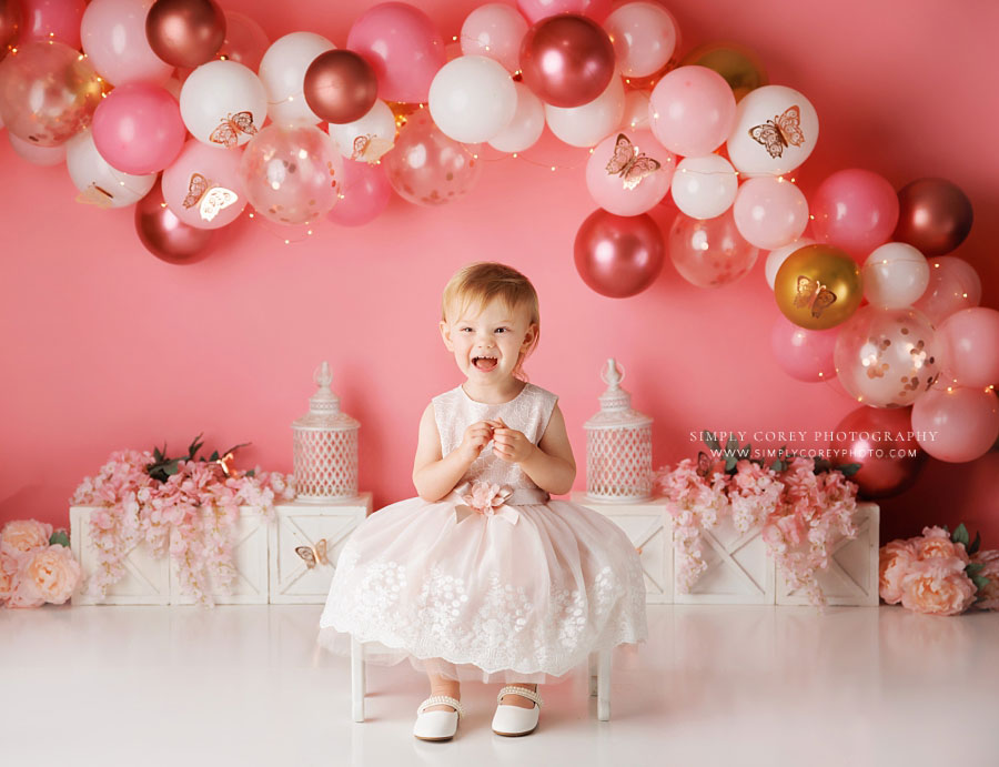 Douglasville baby photographer, girl laughing on studio set with balloons