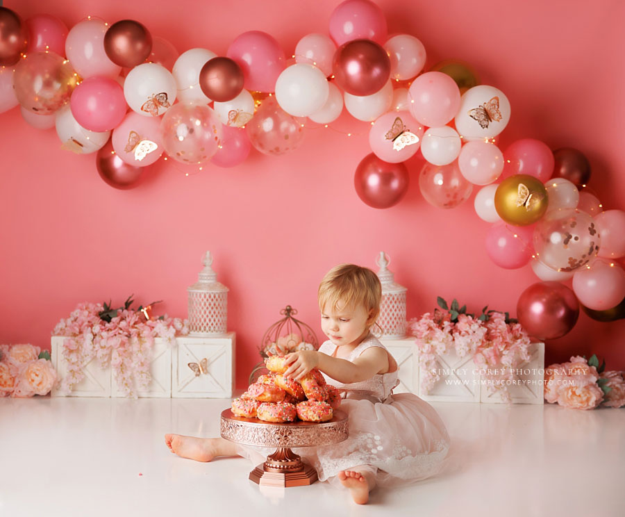 Newnan cake smash photographer, baby eating donuts with pink balloons and butterflies
