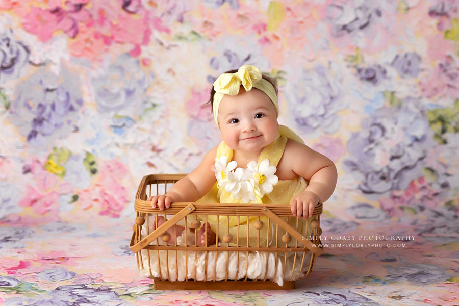 Hiram baby photographer, six month old girl in basket on floral backdrop
