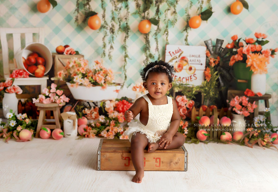 baby photographer near Newnan, girl on wooden crate with peach themed studio set