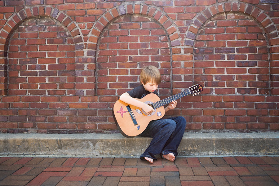 Atlanta kids' photographer, boy playing acoustic guitar outside in Marietta