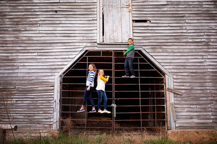 Carrollton family photographer, children climbing barn gate