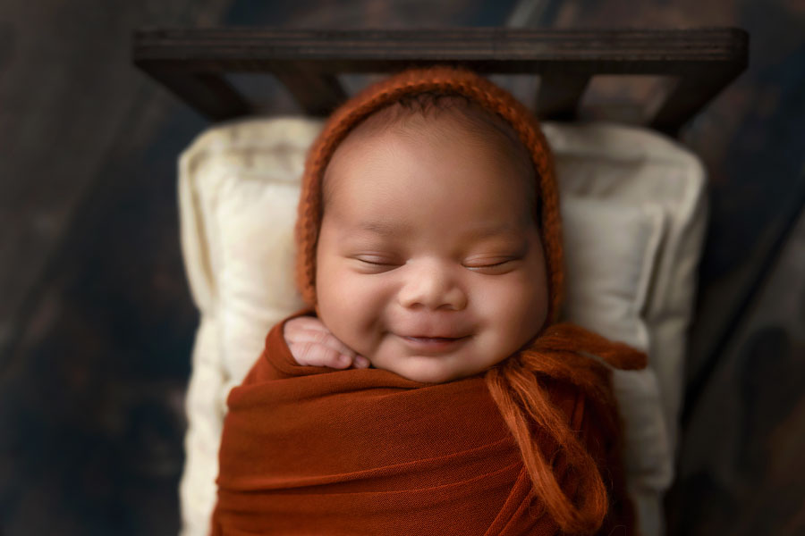 Dallas Georgia newborn photographer, baby boy smiling in burnt orange swaddle set