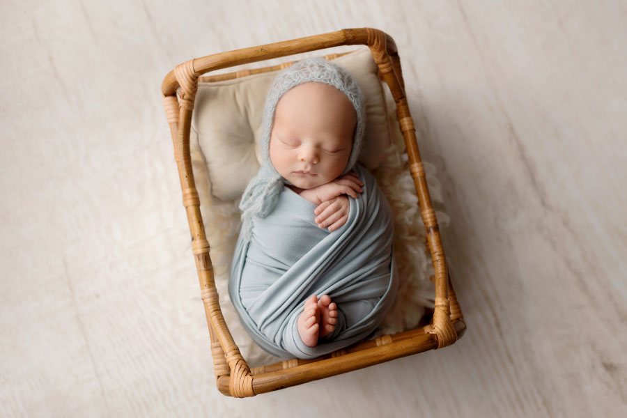 Hiram newborn photographer, baby boy in blue set with crib prop