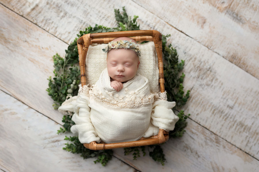 newborn photographer near Carrollton, GA; baby girl in off white with greenery