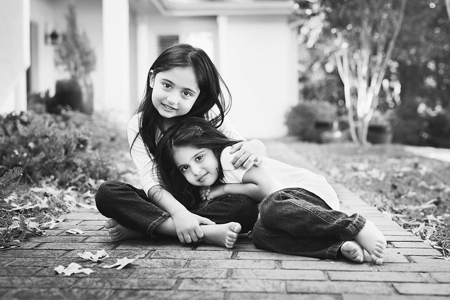 Newnan children's photographer, sisters outside walkway at home in black and white