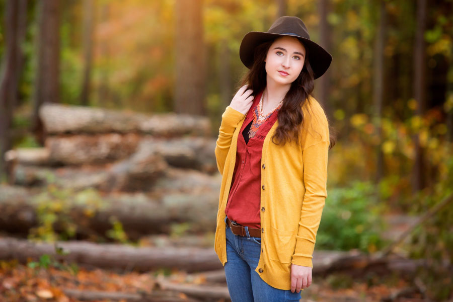 senior portrait photographer near Carrollton, GA; teen girl outside in country by log pile